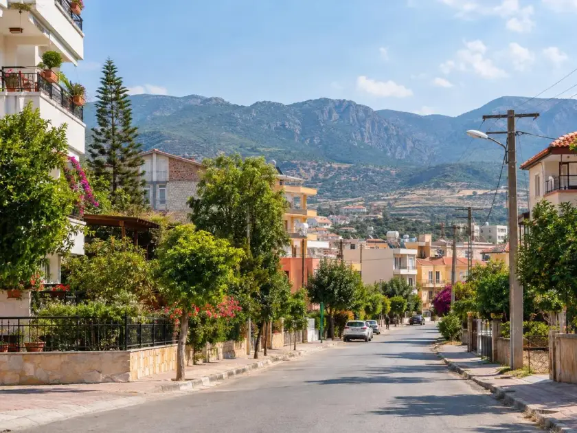 Editorial rendering of a residential street for an article about Anamur: houses, greenery, and mountains in the background